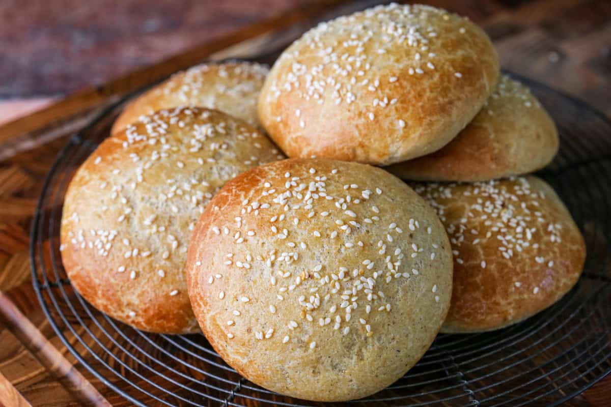 Burger Buns on wire rack cooling, golden brown and scattered with sesame seeds.