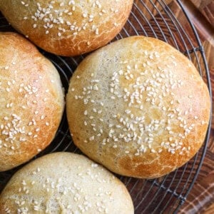 Burger Buns on wire rack cooling, golden brown and scattered with sesame seeds.