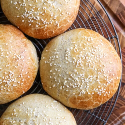 Burger Buns on wire rack cooling, golden brown and scattered with sesame seeds.