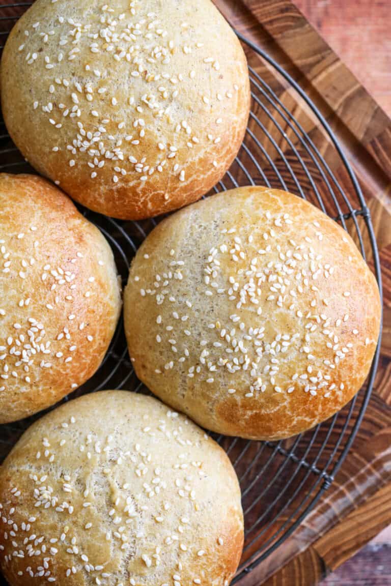 Burger Buns on wire rack cooling, golden brown and scattered with sesame seeds.