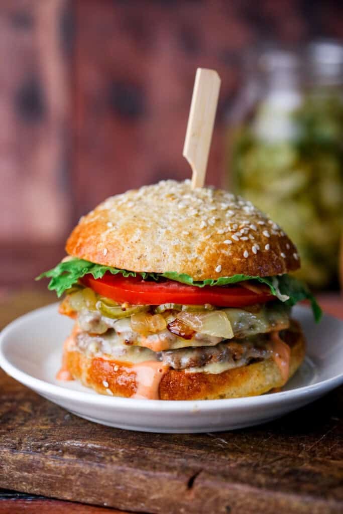 Stacked gluten-free smash burger with all the toppings, held together with wooden skewer.