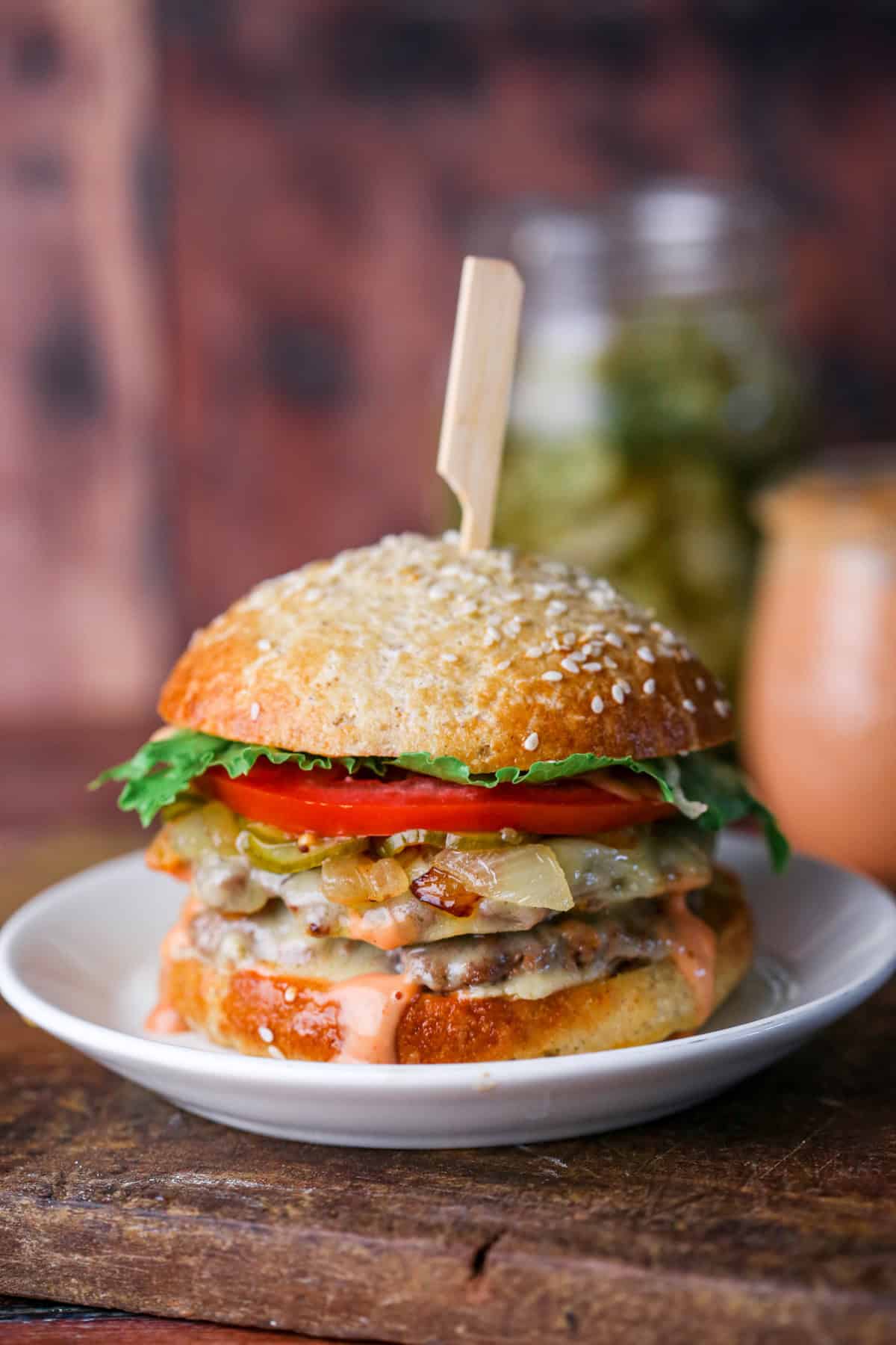 Stacked gluten-free smash burger with all the toppings, held together with wooden skewer.