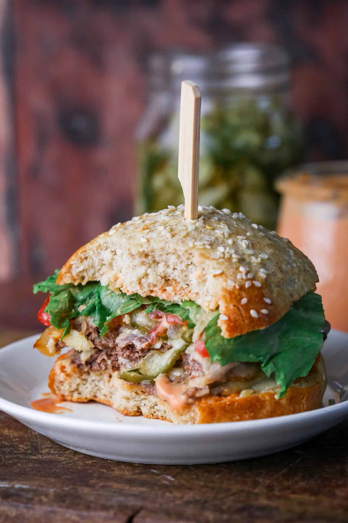 Plate of a gluten-free smash burger, showing beef patties, salad, caramelised onions, cheese and burger sauce wrapped inside a gluten-free burger bun.