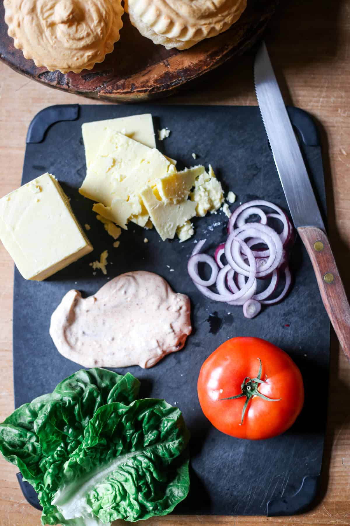 Toppings for meatloaf burgers on a board.