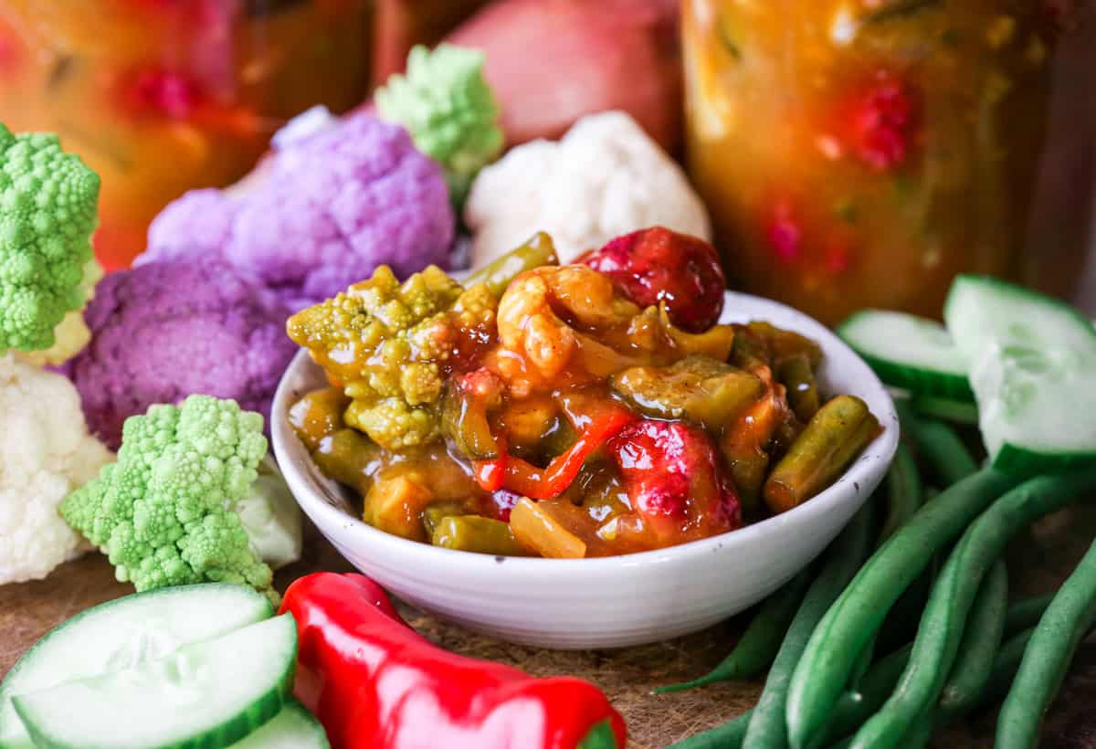 Portion of piccalilli in bowl surrounded by ingredients.