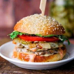 Stacked gluten-free smash burger with all the toppings, held together with wooden skewer.